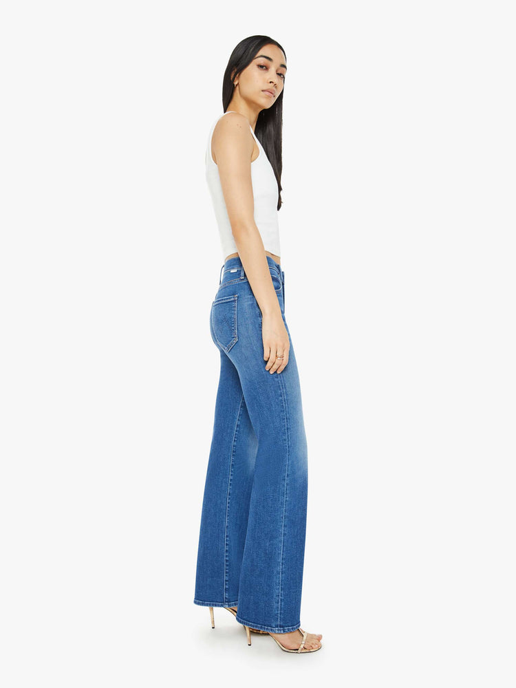 Side view of a woman in a medium blue wash high-rise straight leg with a 32-inch inseam and a clean hem jean.