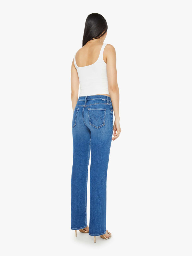 Back view of a woman in a medium blue wash high-rise straight leg with a 32-inch inseam and a clean hem jean.