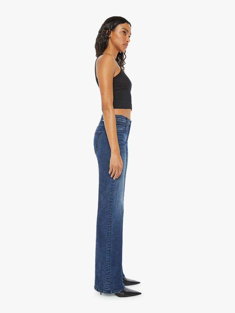 Side view of a woman in a dark blue high-rise straight leg jean with a 30-inch inseam and a clean hem.