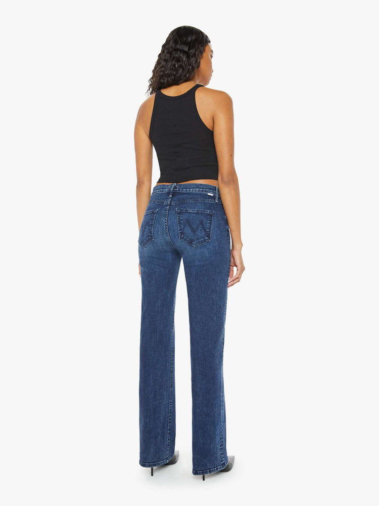 Back view of a woman in a dark blue high-rise straight leg jean with a 30-inch inseam and a clean hem.