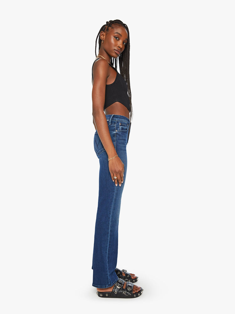 Side view of a woman dark blue high-waisted bootcut with a 32-inch inseam and a clean hem.