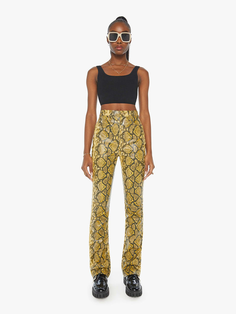 Front view of a woman in a yellow and black faux snakeskin super high-waisted pants with a flared leg and a long 34-inch inseam with a clean hem.