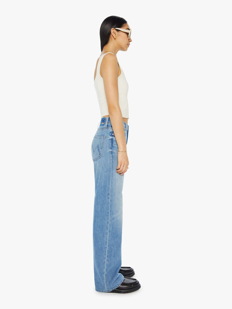 Side view of a woman in light blue denim set to sit lower on the hips with a loose straight left and clean hem.