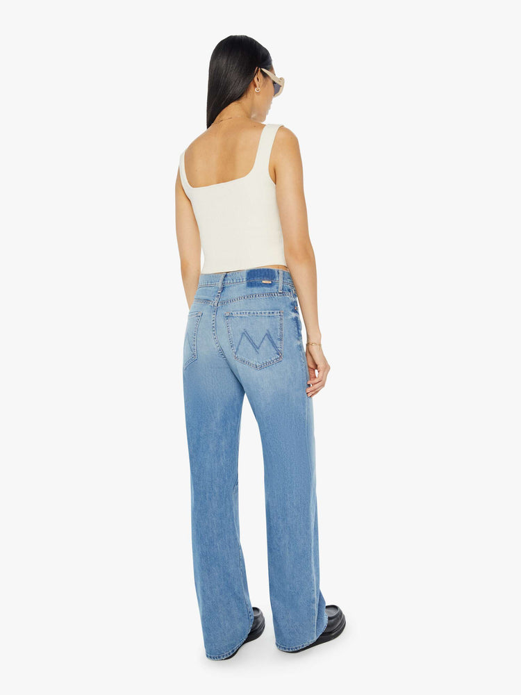 Back view of a woman in light blue denim set to sit lower on the hips with a loose straight left and clean hem.