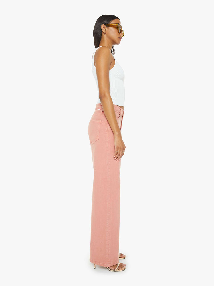 Side view of a woman in light coral pants designed to sit on the hips with a slouchy fit, a loose straight leg and a 32-inch inseam with a clean hem.