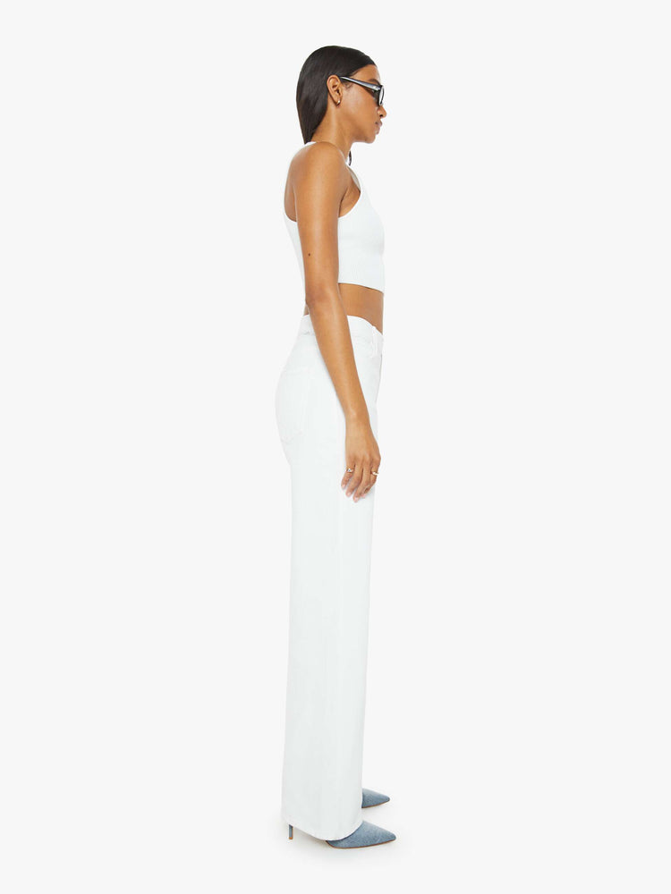 Side view of a woman in a white denim designed to sit on the hips with a slouchy fit, this loose straight leg has a 32-inch inseam with a clean hem. 