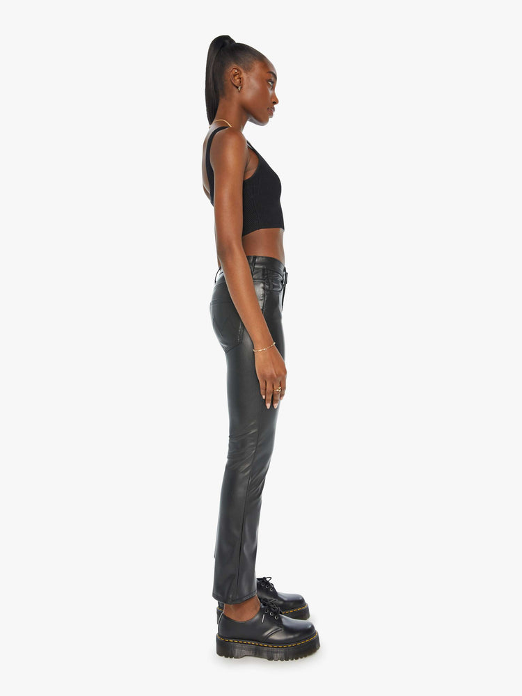 Side view of a woman black faux leather high-rise bootcut has a 28.25-inch inseam and a clean hem.