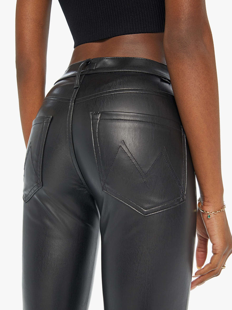 Close up view of a woman black faux leather high-rise bootcut has a 28.25-inch inseam and a clean hem.