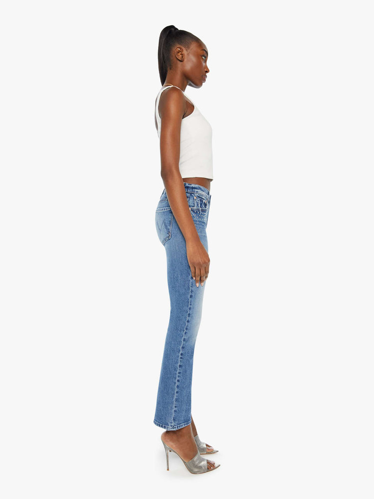 Side view of a woman in a med blue wash mid-rise bootcut has a 28.25-inch inseam and a clean hem.