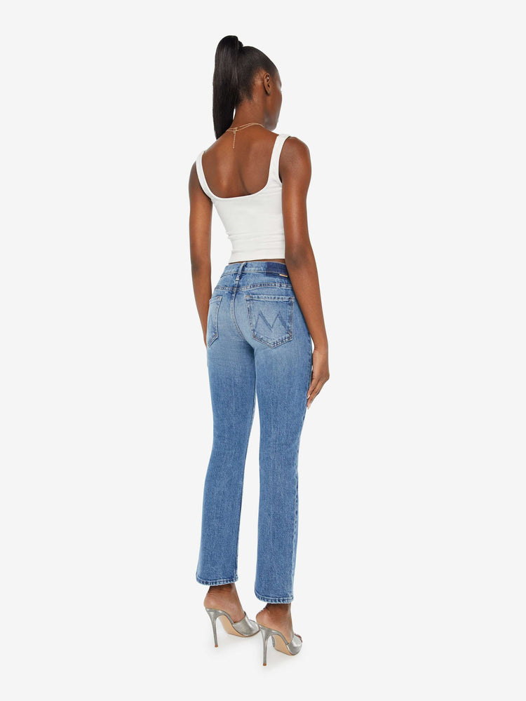 Back view of a woman in a med blue wash mid-rise bootcut has a 28.25-inch inseam and a clean hem.