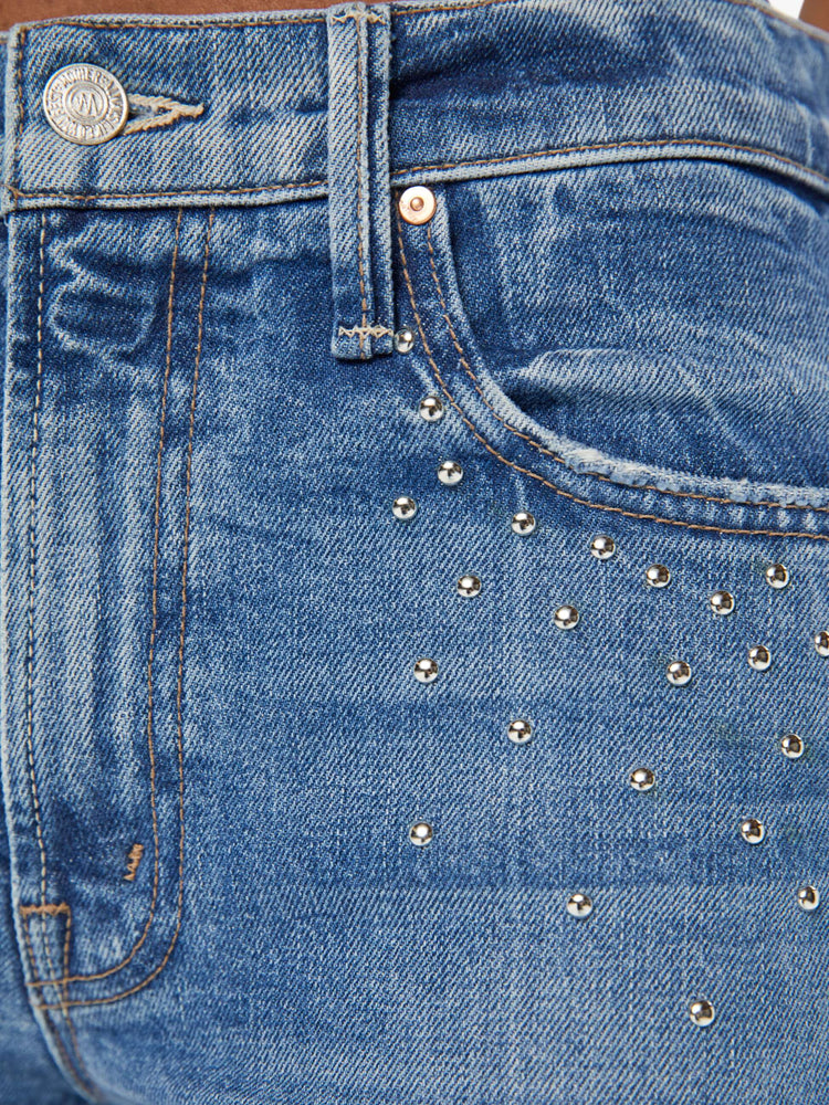 Details view of a woman in a med blue wash mid-rise bootcut has a 28.25-inch inseam and a clean hem.