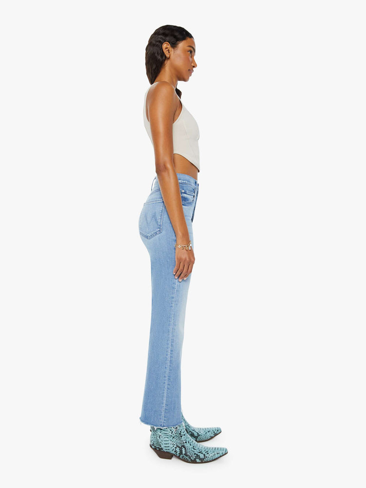 Side view of a woman in a light blue high-rise flare with a button fly and a frayed hem that hits at the ankle.