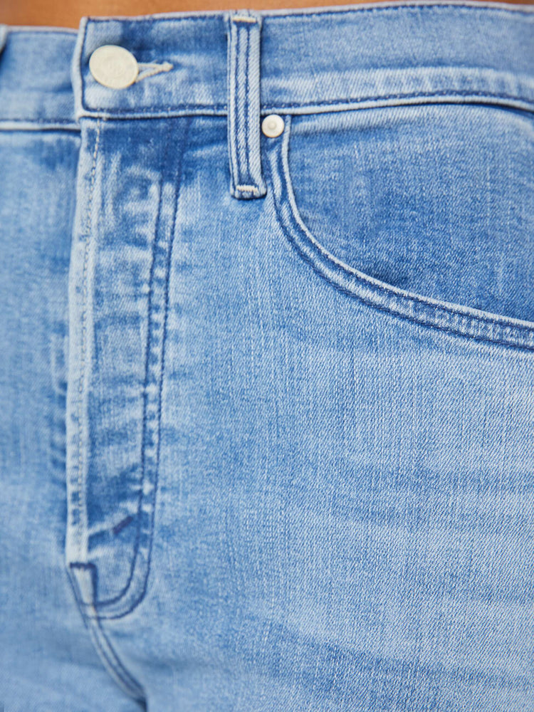 Detailed view of a woman in a light blue high-rise flare with a button fly and a frayed hem that hits at the ankle.