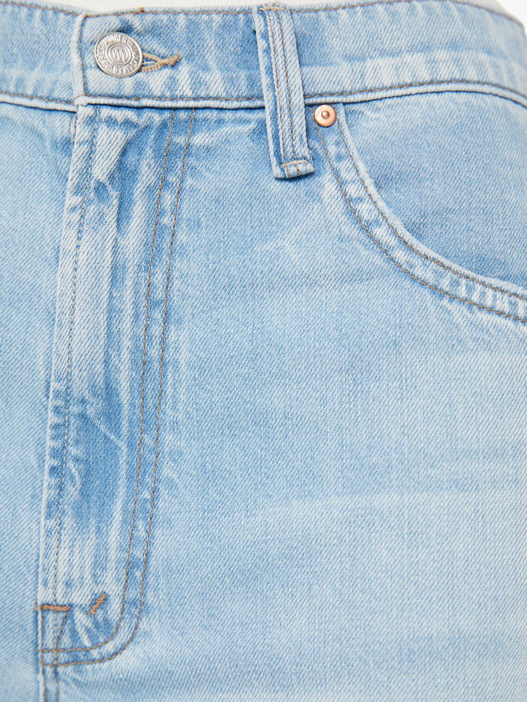 Detailed view of a woman in light blue super high-rise jeans with a loose wide leg, zip fly and a long 34-inch inseam with a clean hem. 