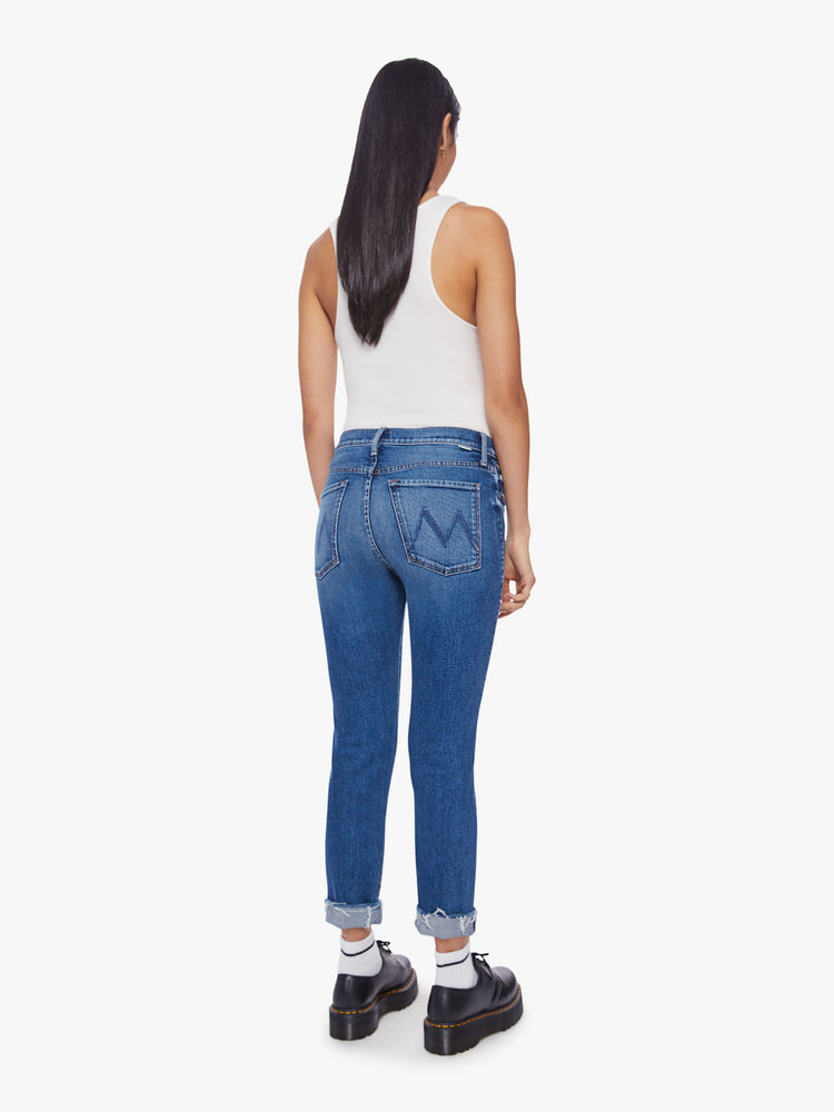 Back view of a woman button-fly jeans with a high rise and an ankle-length hem that's cuffed and frayed in a classic blue hue.
