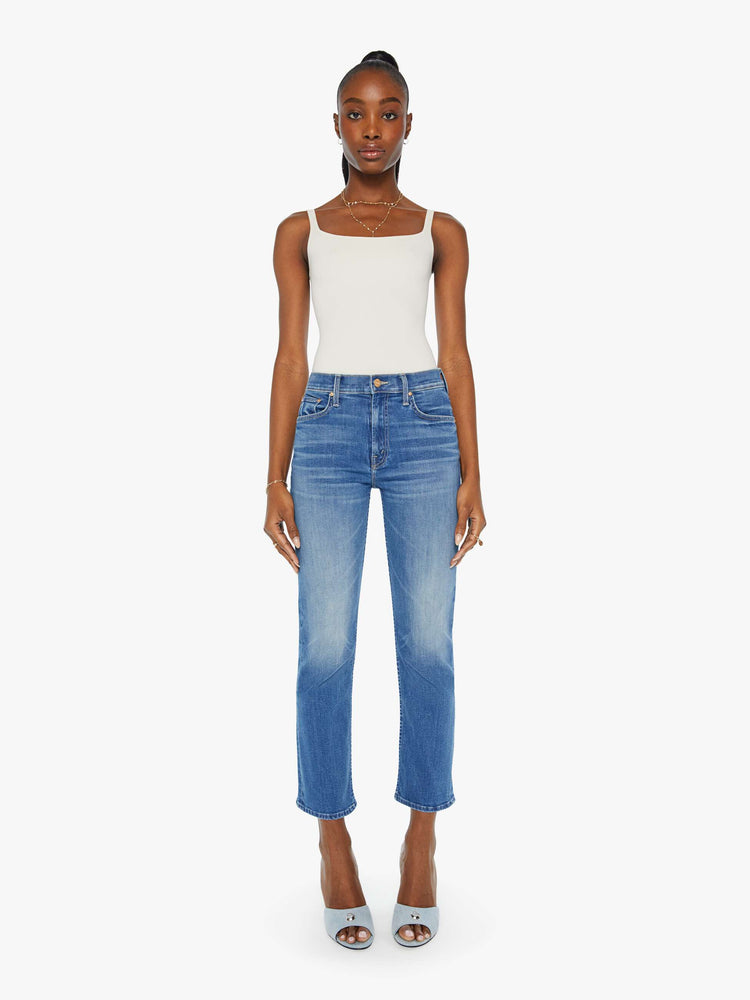 Front view of a woman in a mid blue wash mid rise straight leg jean with an ankle length inseam.