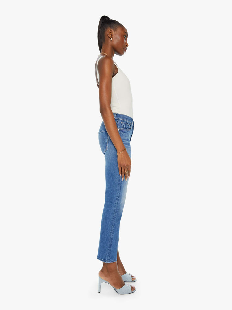 Side view of a woman in a mid blue wash mid rise straight leg jean with an ankle length inseam.