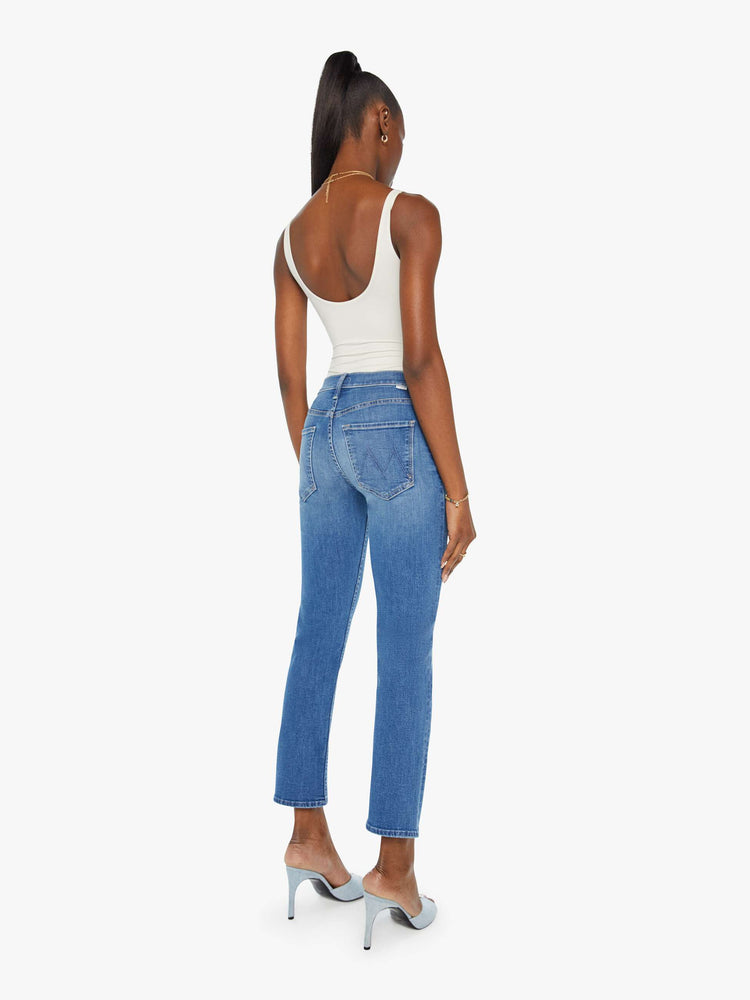 Back view of a woman in a mid blue wash mid rise straight leg jean with an ankle length inseam.