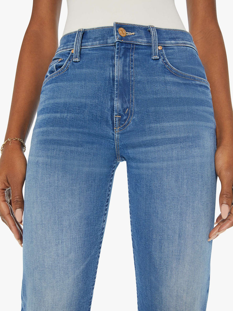 Close up view of a woman in a mid blue wash mid rise straight leg jean with an ankle length inseam.