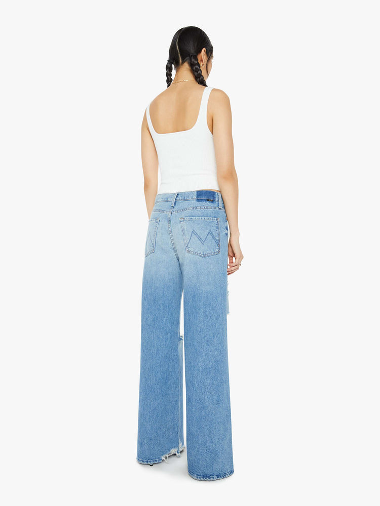 Back view of the woman in a mid blue wide-leg jeans feature a button fly, low-set back pockets, mid rise with a slightly dropped crotch and a 32-inch inseam. 