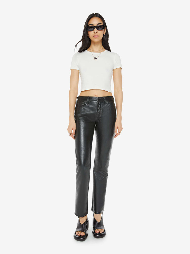 Front view of a woman in a recycled black leather high waisted straight-leg pants with a 31-inch inseam and a clean hem.