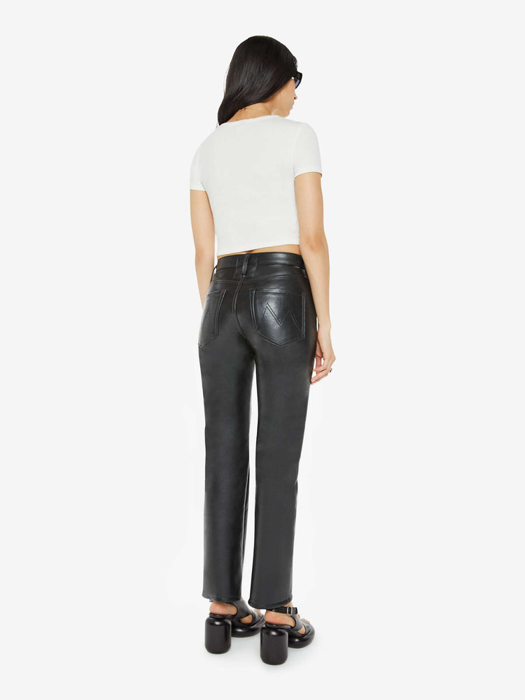 Back view of a woman in a recycled black leather high waisted straight-leg pants with a 31-inch inseam and a clean hem.