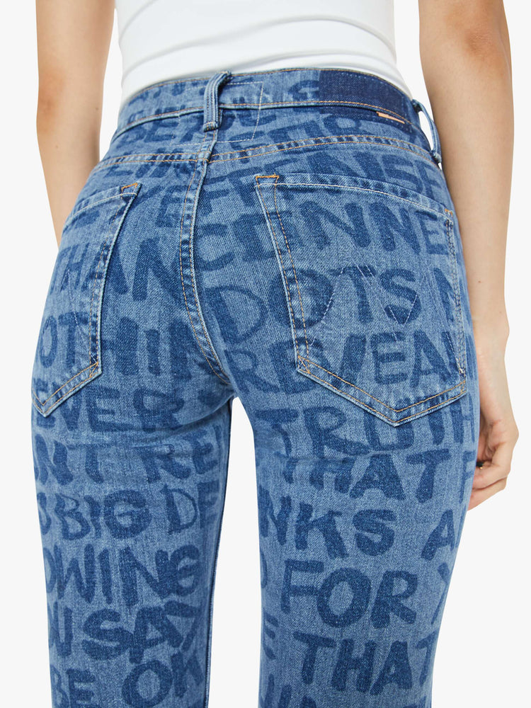 Back view of a woman in a high waisted straight-leg jeans with a 31-inch inseam and a clean hem in a mid blue wash with laser-processed text in dark blue throughout.