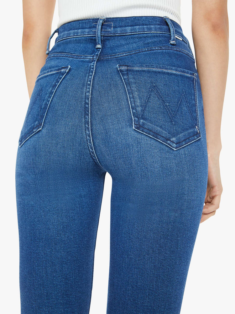 Back view of a woman dark blue high-rise bootcut has a 28.25-inch inseam and a frayed hem.