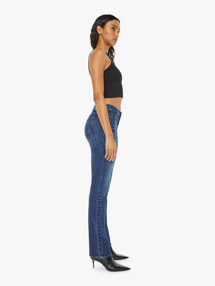 Side view of a woman in dark blue mid-rise straight leg with a long 31-inch inseam and a clean hem.