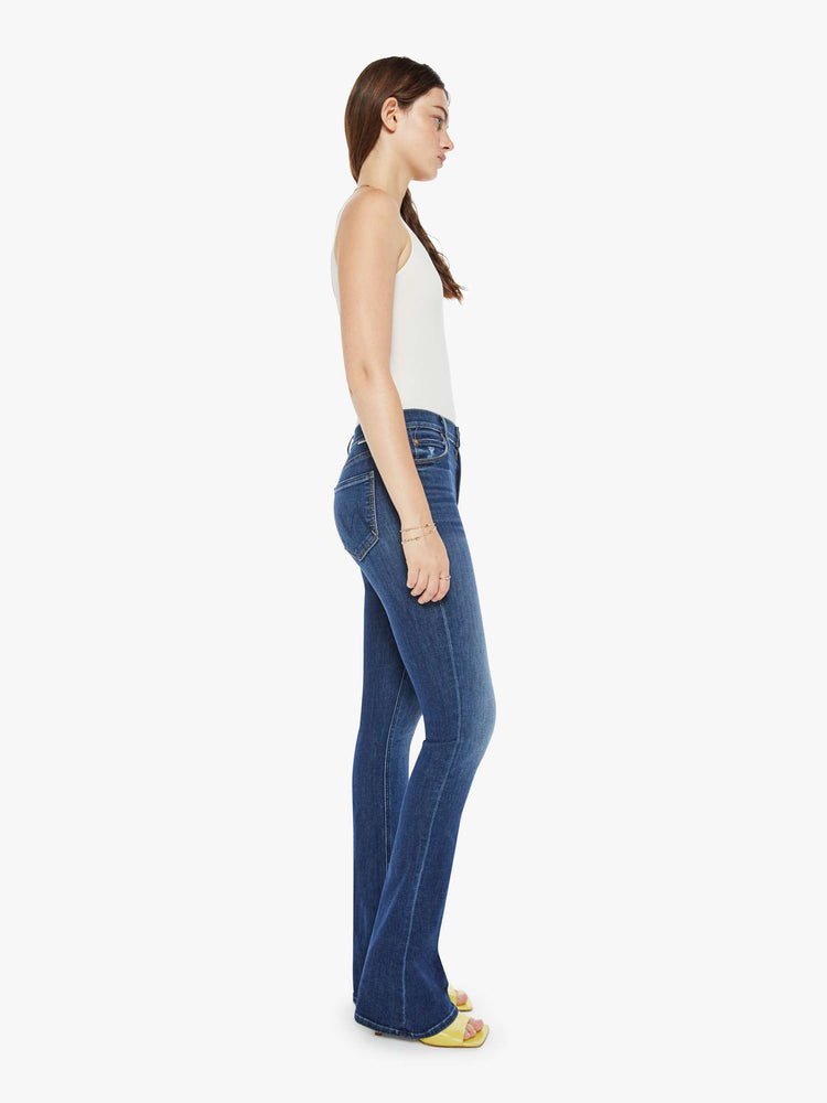 Side view of a dark blue wash denim skinny flare featuring a high rise.