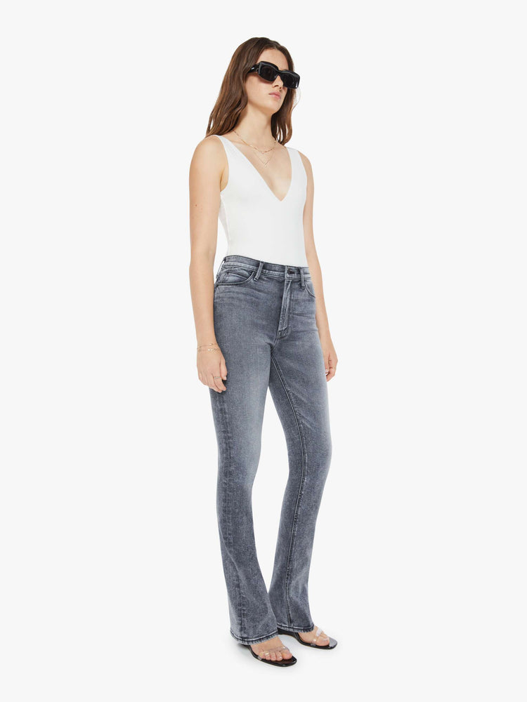 Side angle view of a womens grey wash flare jean featuring a high rise, and a long clean hem.