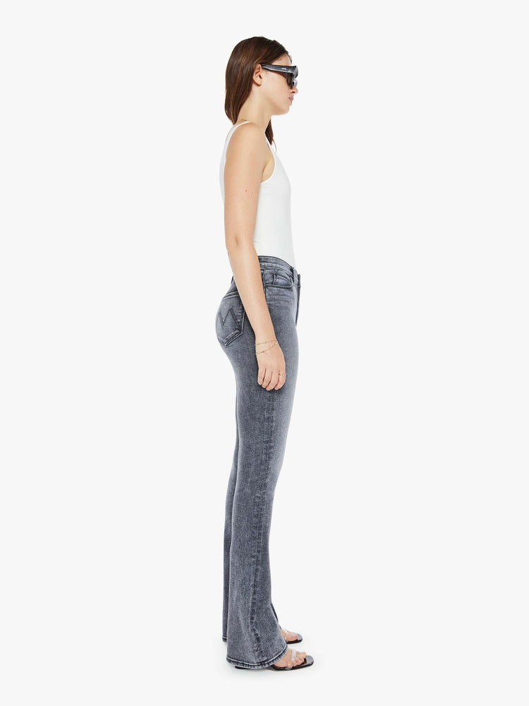 Side view of a womens grey wash flare jean featuring a high rise, and a long clean hem.