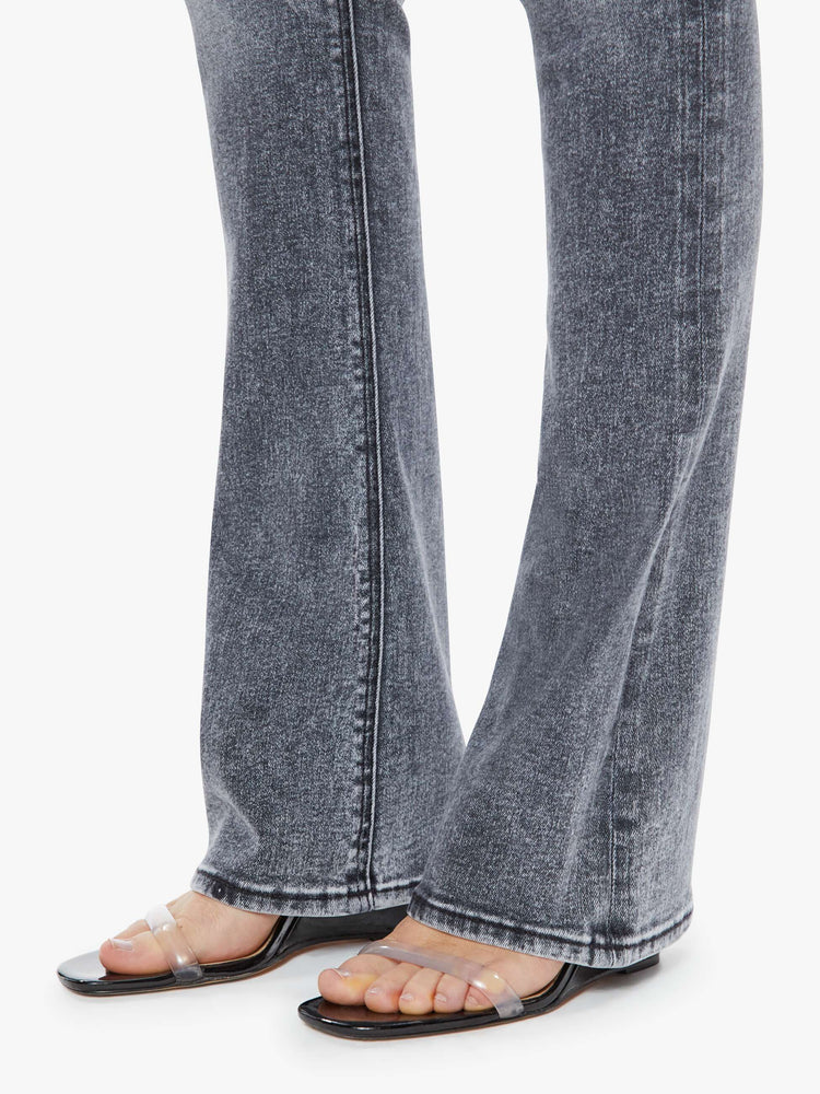 Hem close up view of a womens grey wash flare jean featuring a high rise, and a long clean hem.