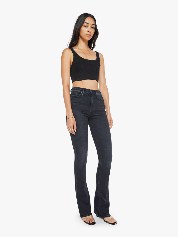 Side angle view of a womens high rise flare jean featuring a dark black wash and a clean hem.