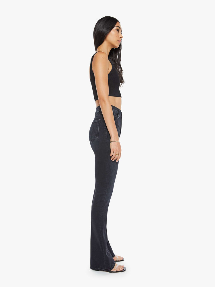 Side view of a womens high rise flare jean featuring a dark black wash and a clean hem.