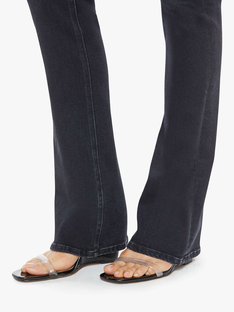 Hem close up view of a womens high rise flare jean featuring a dark black wash and a clean hem.