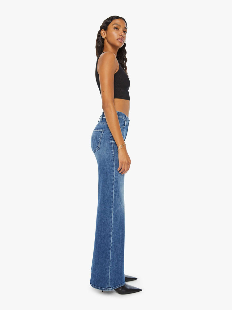 Side view of a woman in medium blue wide leg jeans with a high rise, 31-inch inseam and a clean hem. 