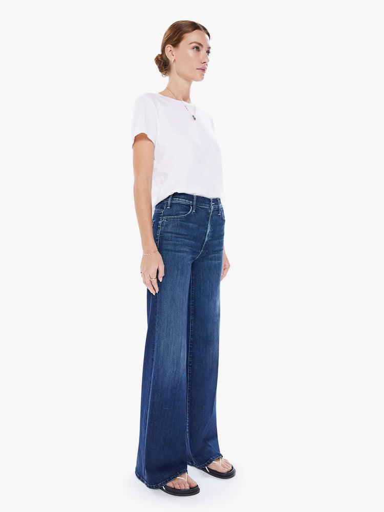 Side angled view of a woman wide leg jeans with a high rise, 32-inch inseam and a clean hem in a dark blue wash.