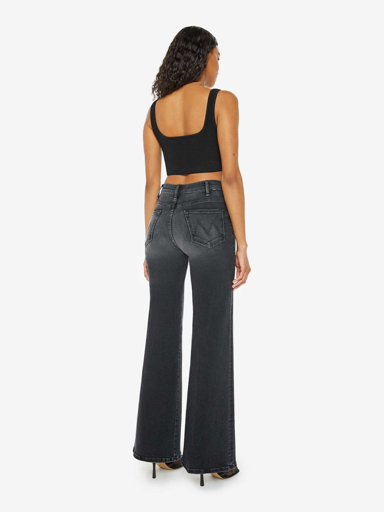 Back view of a woman in a black wash  wide leg jeans with a high rise, 30-inch inseam and a clean hem. 