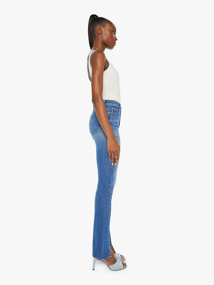 Side view of a woman in a med blue high-rise straight leg jean with a long 34-inch inseam and a split front hem.