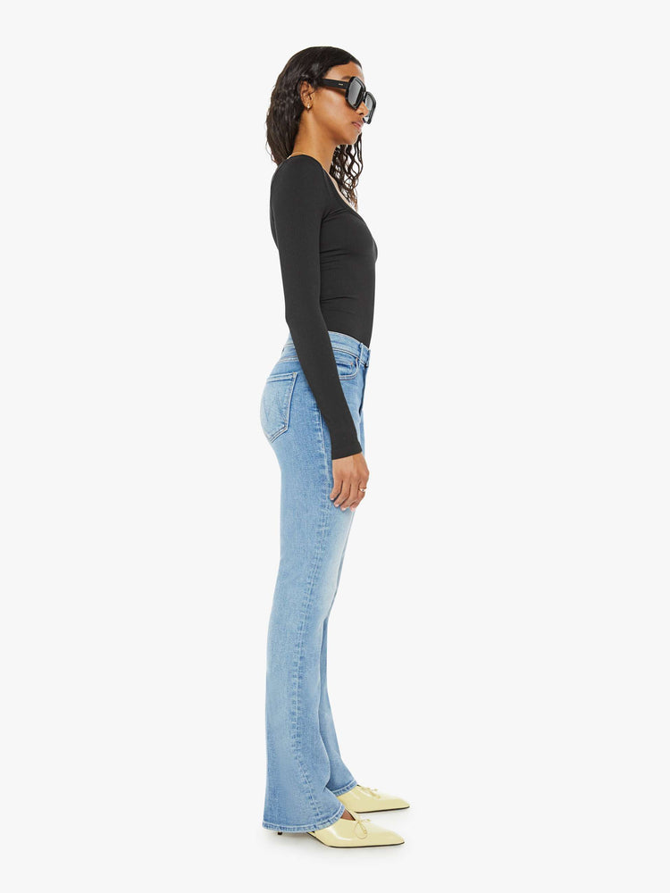 Side view of a woman midblue wash flare jeans with a mid rise and a long 32-inch inseam with a clean hem.