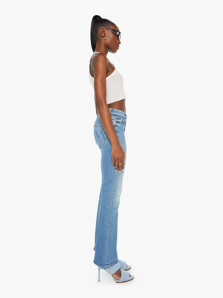 Side view of a woman in mid rise flare jean in a light blue wash. 