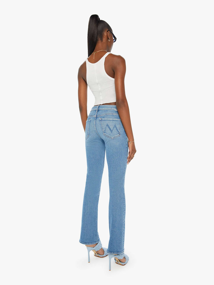 Back view of a woman in mid rise flare jean in a light blue wash. 