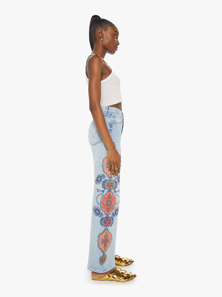 Side view of a high rise wide leg jean in a light blue wash with printed pattern down the side of each leg.