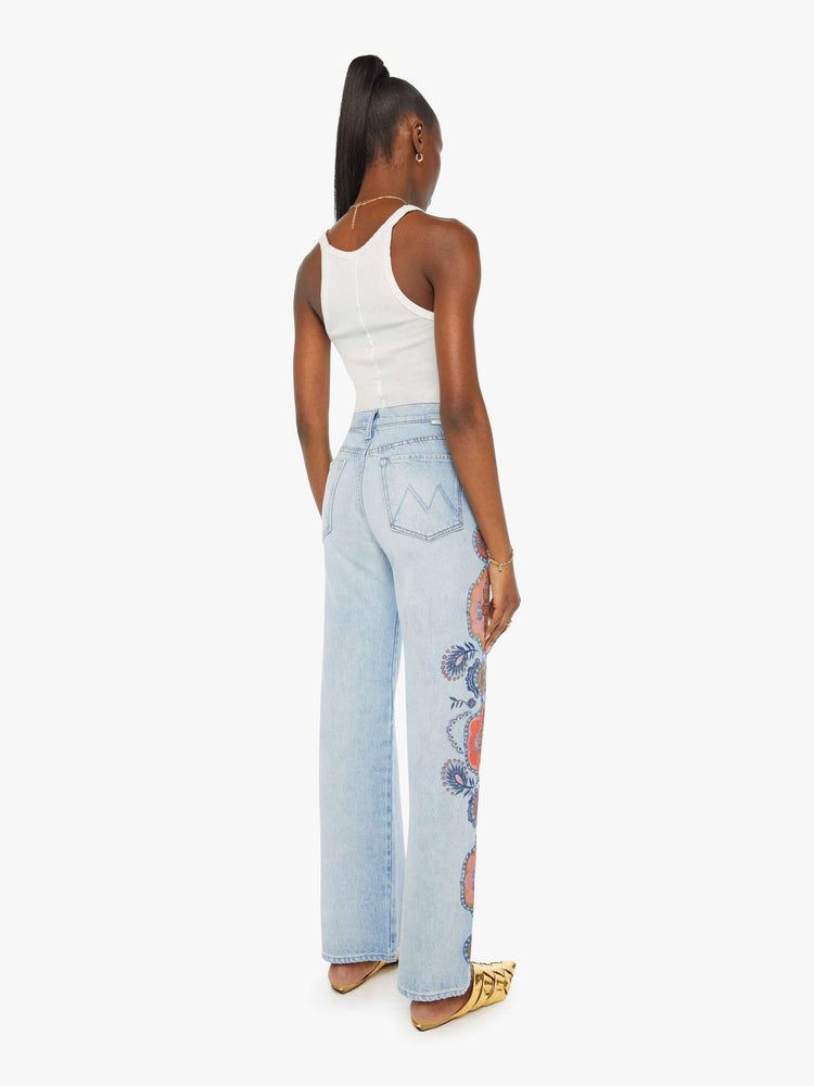 Back view of a high rise wide leg jean in a light blue wash with printed pattern down the side of each leg.