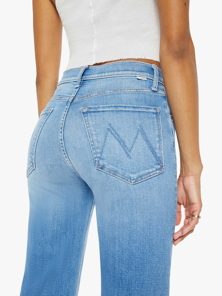 Back view of a woman medium blue wash high-waisted jeans with a wide straight leg, zip fly and clean 28.25-inch inseam.