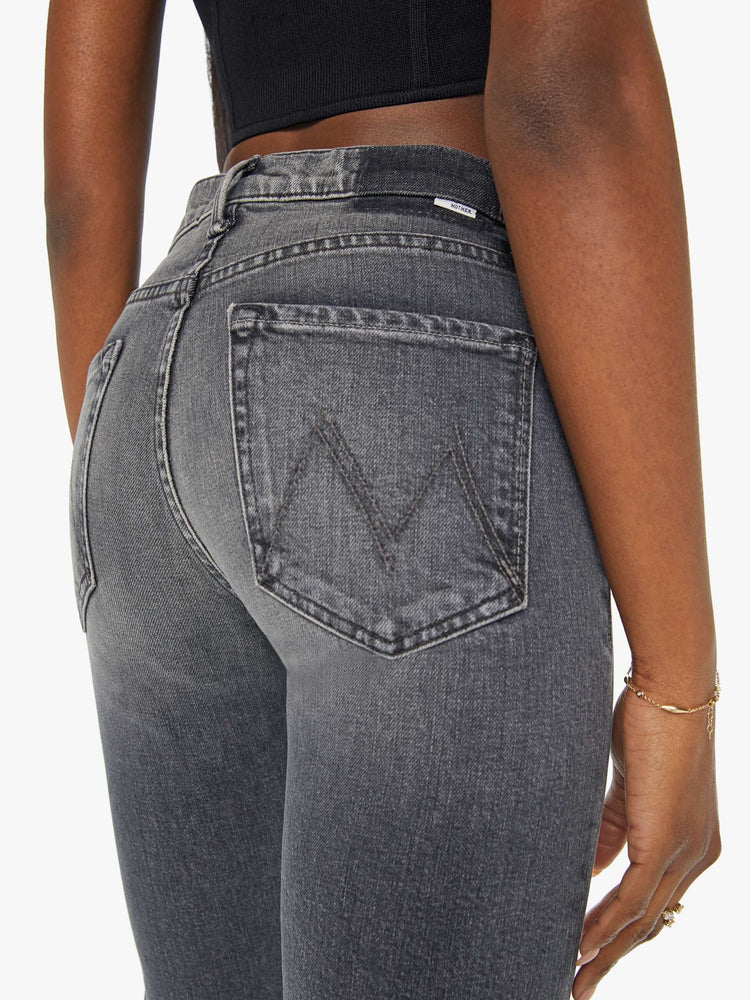 Detailed back view of a woman in mid-rise dark grey straight leg jeans with a clean hem.