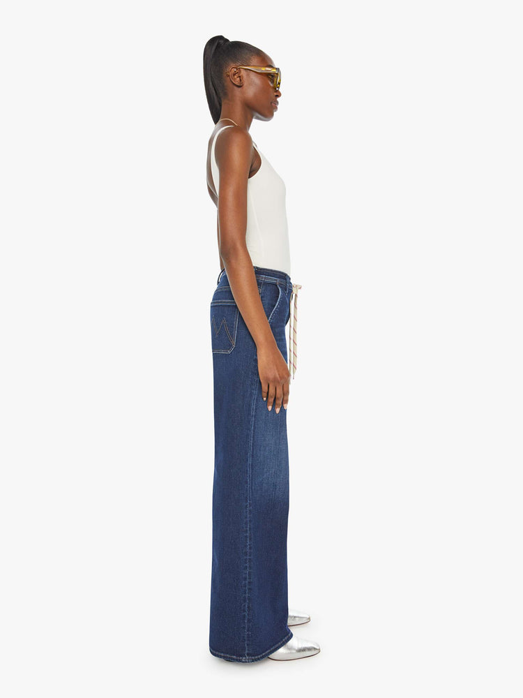 Side view of a woman in a dark blue high-rise wide leg with a drawstring waist, side-slit pockets and a long 32-inch inseam with a clean hem.