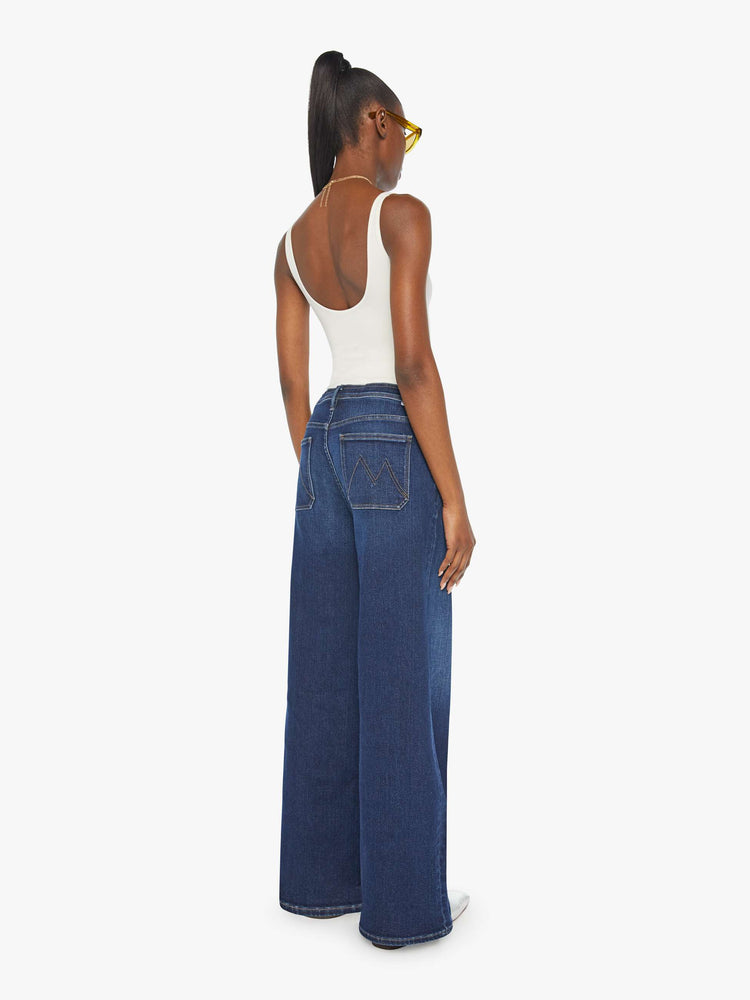 Back view of a woman in a dark blue high-rise wide leg with a drawstring waist, side-slit pockets and a long 32-inch inseam with a clean hem.