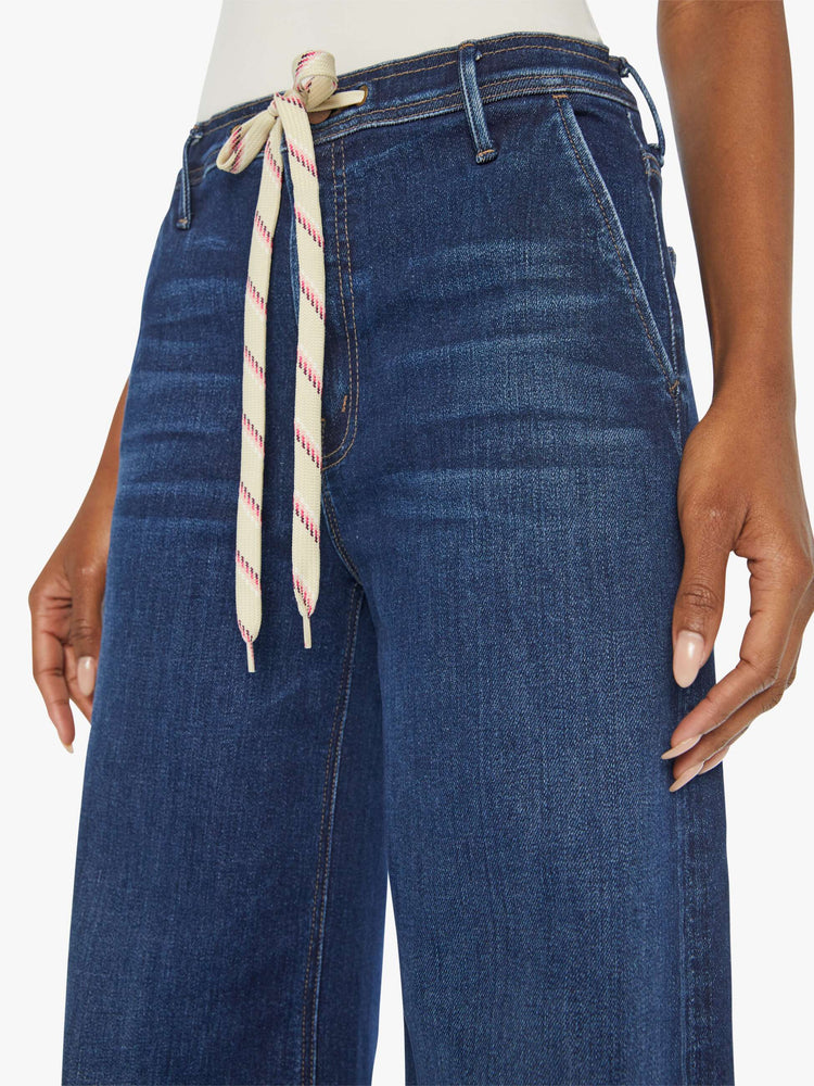 Waist close up view of a woman in a dark blue high-rise wide leg with a drawstring waist, side-slit pockets and a long 32-inch inseam with a clean hem.